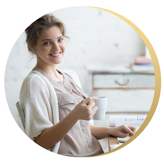 Happy young woman at desk with coffee in hand reflecting on her counseling for anxiety experience with Delia Counseling Services in Yakima.