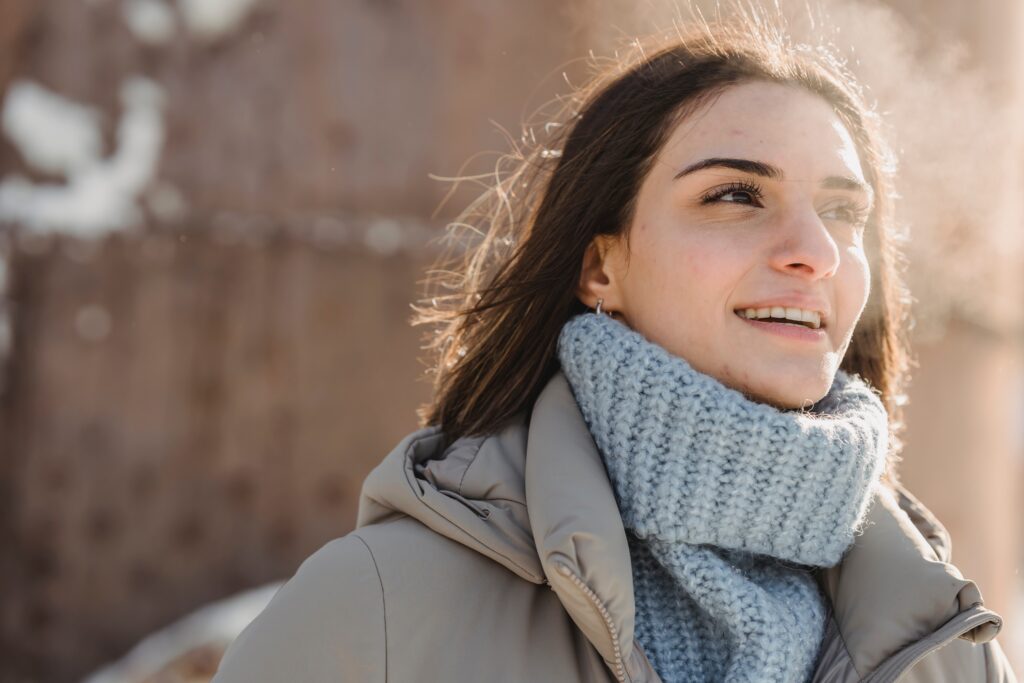 This is an image of a young woman walking in the cold with a turtleneck and coat who is looking off into the distance with a positive expression. She appears hopeful and confident about her ability to banish negative thoughts after her therapy sessions at Susan Delia Counseling Center in Yakima.