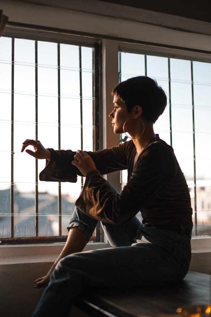 Image of a woman silhouetted against a window, looking out and wondering, "Do I have PTSD?"