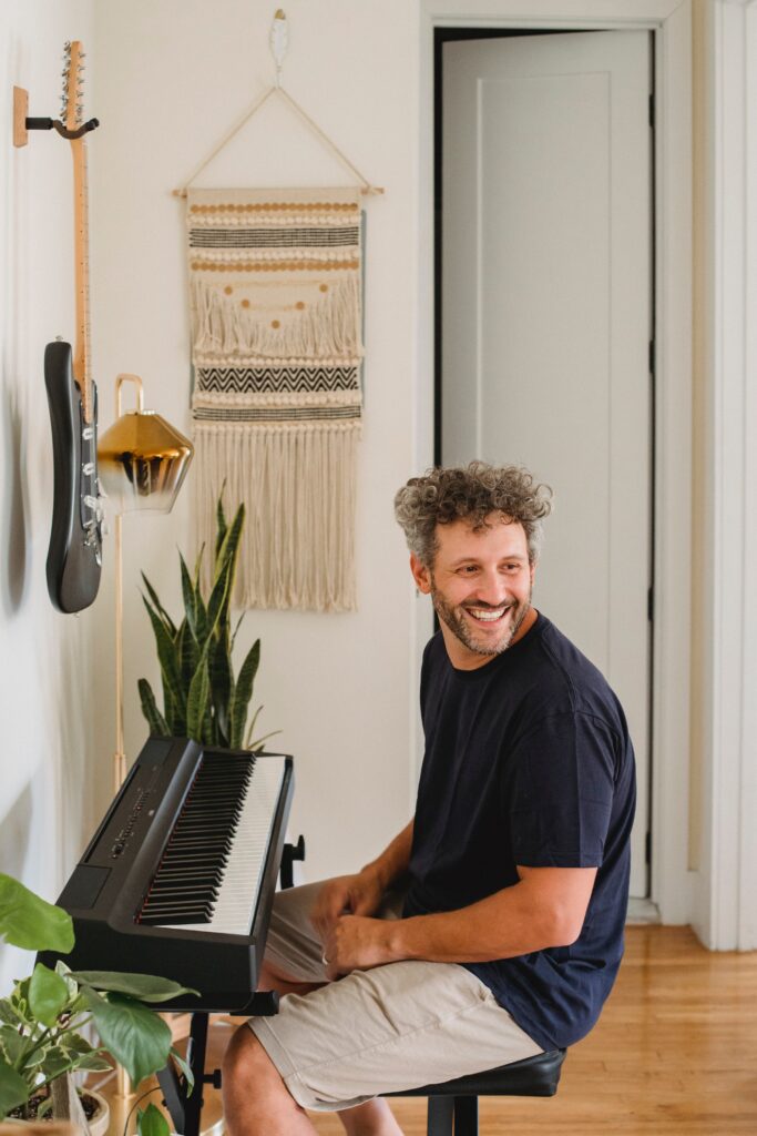 A client of Susan Delia's sits at his keyboard and smiles, feeling happy relieved after his therapy session