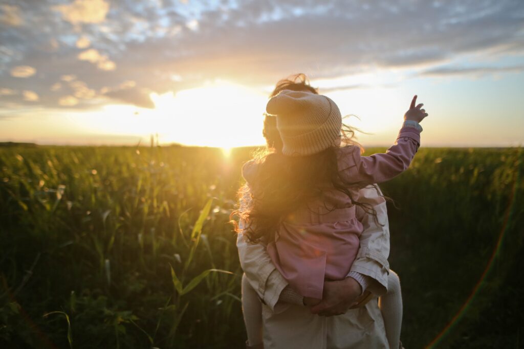 a mother and child standing in a sunny field as the mother thinks about how to protect her children from a toxic relationship