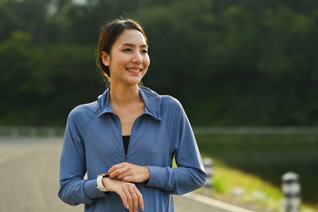 Sporty woman resting after jogging in the park. Healthy lifestyle, workout and wellness concept.