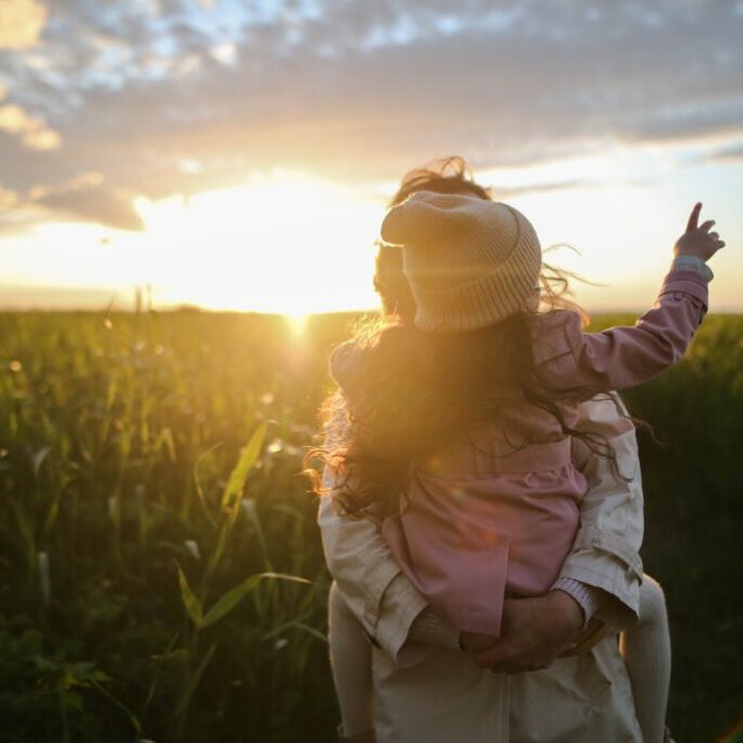 a mother and child standing in a sunny field as the mother thinks about how to protect her children from a toxic relationship