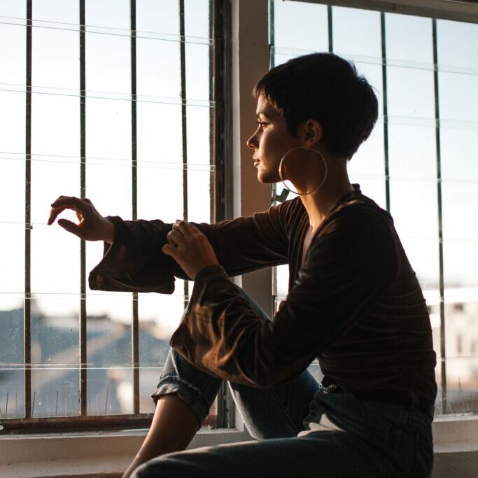 Image of a woman silhouetted against a window, looking out and wondering, "Do I have PTSD?"